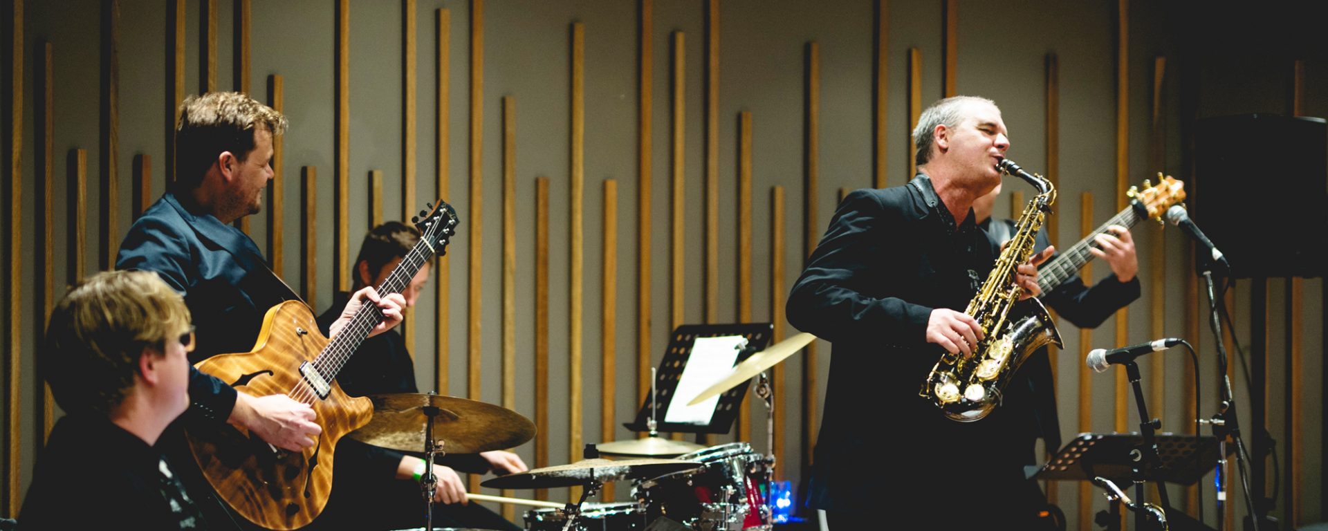 And Firth playing saxophone live on stage with band in foreground